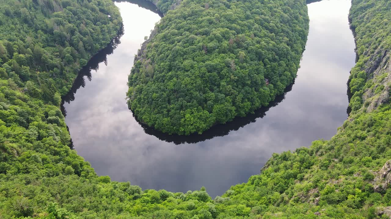 Winding river, tranquil bend, lush green hills, calm water reflections, idyllic
