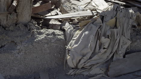 rubble in the sand, deteriorated cloth, wood and stone lie in heap in desert