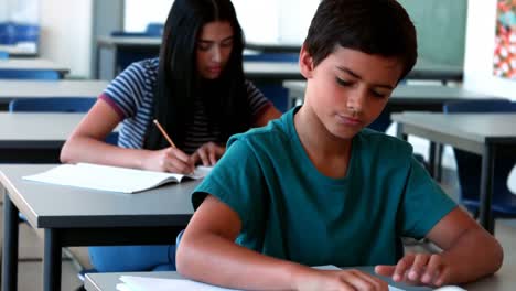 schoolboy using mobile phone while studying in classroom