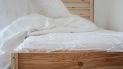 unmade bed with white sheets and wooden frame