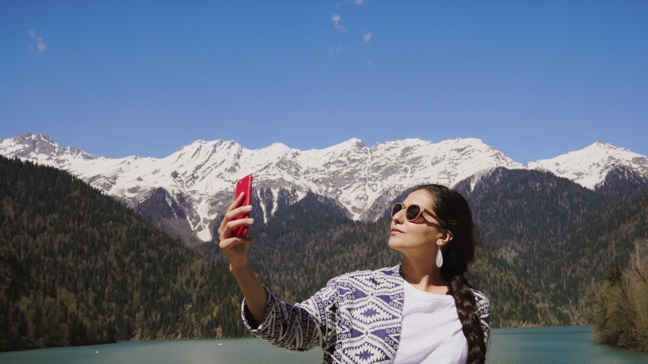 mujer tomando una selfie contra un fondo de lago de montaña
