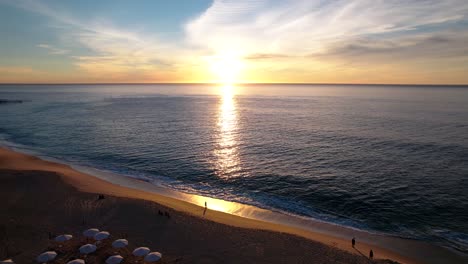 aerial of a sunrise over a cabo beach and a calm sea with vibrant colors
