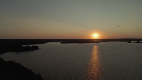 slow aerial dolly in over lake in boreal forest, sunset