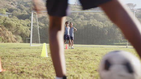 standing on soccer field, kids preparing for practice with cones and goal net