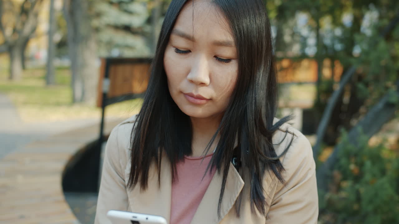 공원에서 스마트폰을 사용하는 여성