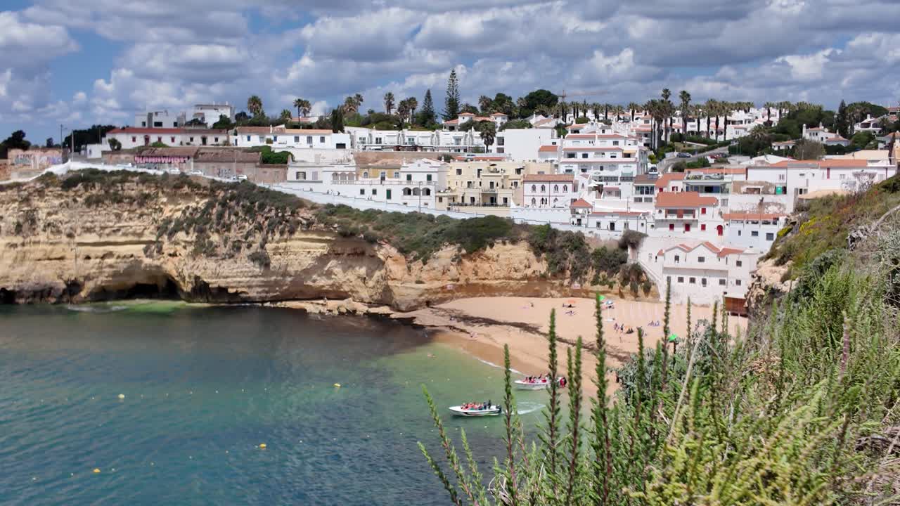 Sunlit beach and village on Algarve coast, Carvoeiro Portugal