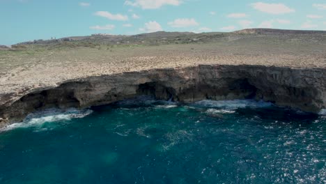 Side-View-Of-A-Rocky-Shore-Line-In-Malta,-With-Waves-Splashing