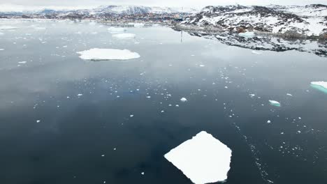 drone reveal remote snowy greenland coastal over floating iceberg