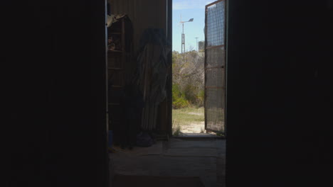 view from a shed's open door to a coastal landscape with wind turbine