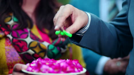 un hombre tomando unas tijeras de un plato de pétalos de rosa que da una chica, de cerca, una chica asiática vestida de amarillo