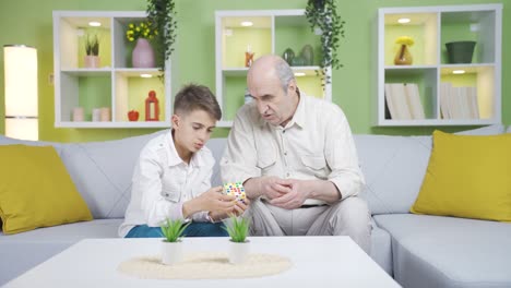 The-child-playing-with-the-intelligence-cube-tries-to-solve-it-with-the-help-of-his-grandfather.