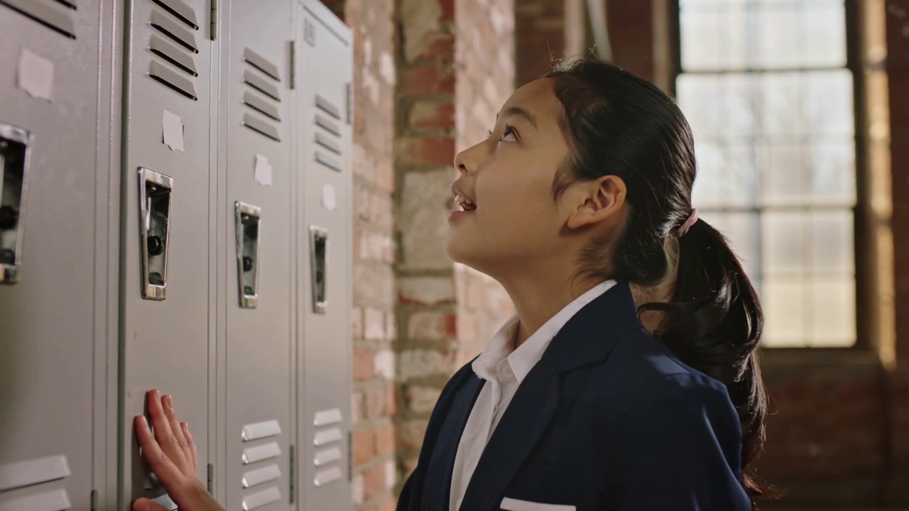 Opening locker, student in navy blazer retrieving folder for class at school hallway, copy space