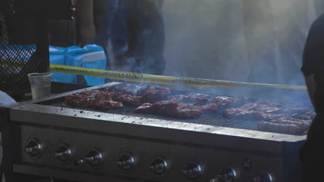 Person-cooks-steak-on-large-barbecue-with-meat-smoking-while-cooking