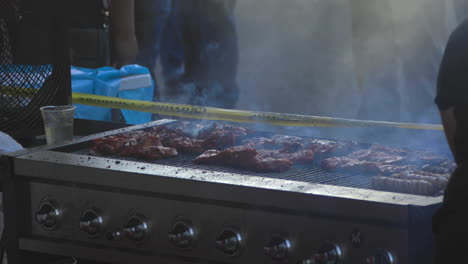 persona cocina bistec en una gran barbacoa con carne ahumada mientras cocina