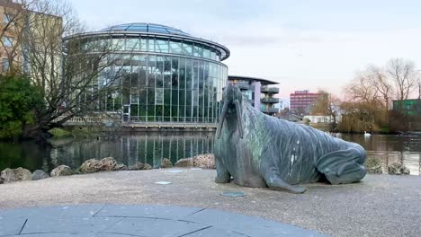 gran estatua de morsa frente a un gran invernadero en un parque de la ciudad