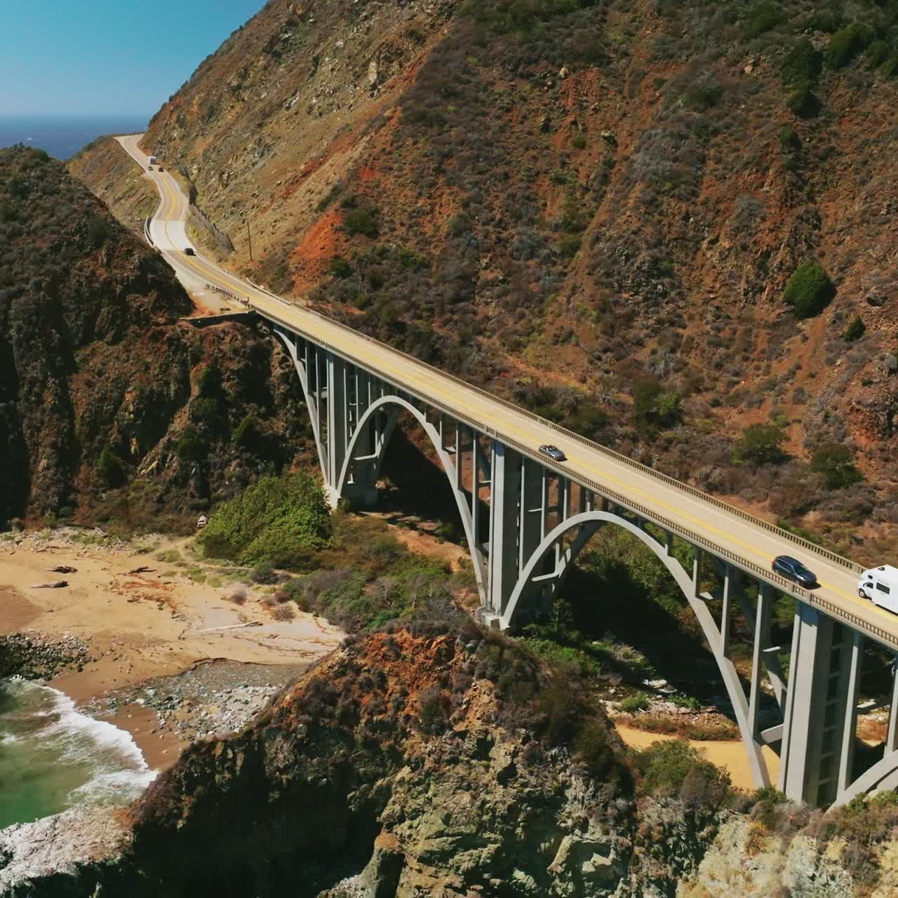 Beautiful bridge connecting the mountains for cars to pass. Lovely sight of Pacific coastline of sunny California from bird's eye view