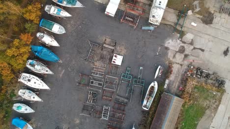 small shipyard with boat parts and finished boats, aerial top down view