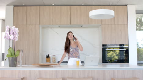 teenage caucasian girl chats on the phone in a modern kitchen