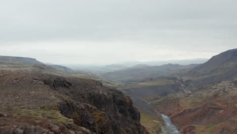 Aerial-view-flying-toward-two-tourist-hiker-enjoying-amazing-panorama-of-Fossa-river-valley-in-Iceland.-Drone-view-revealing-stunning-panorama-of-river-flowing-in-icelandic-mossy-countryside