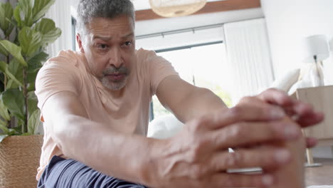 Hombre-Birracial-Senior-Enfocado-Practicando-Yoga,-Estirándose-En-Casa,-Cámara-Lenta