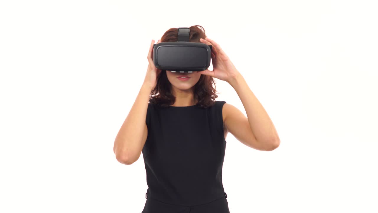 mujer joven atractiva en vestido negro tomando y usando gafas de realidad virtual aisladas sobre blanco