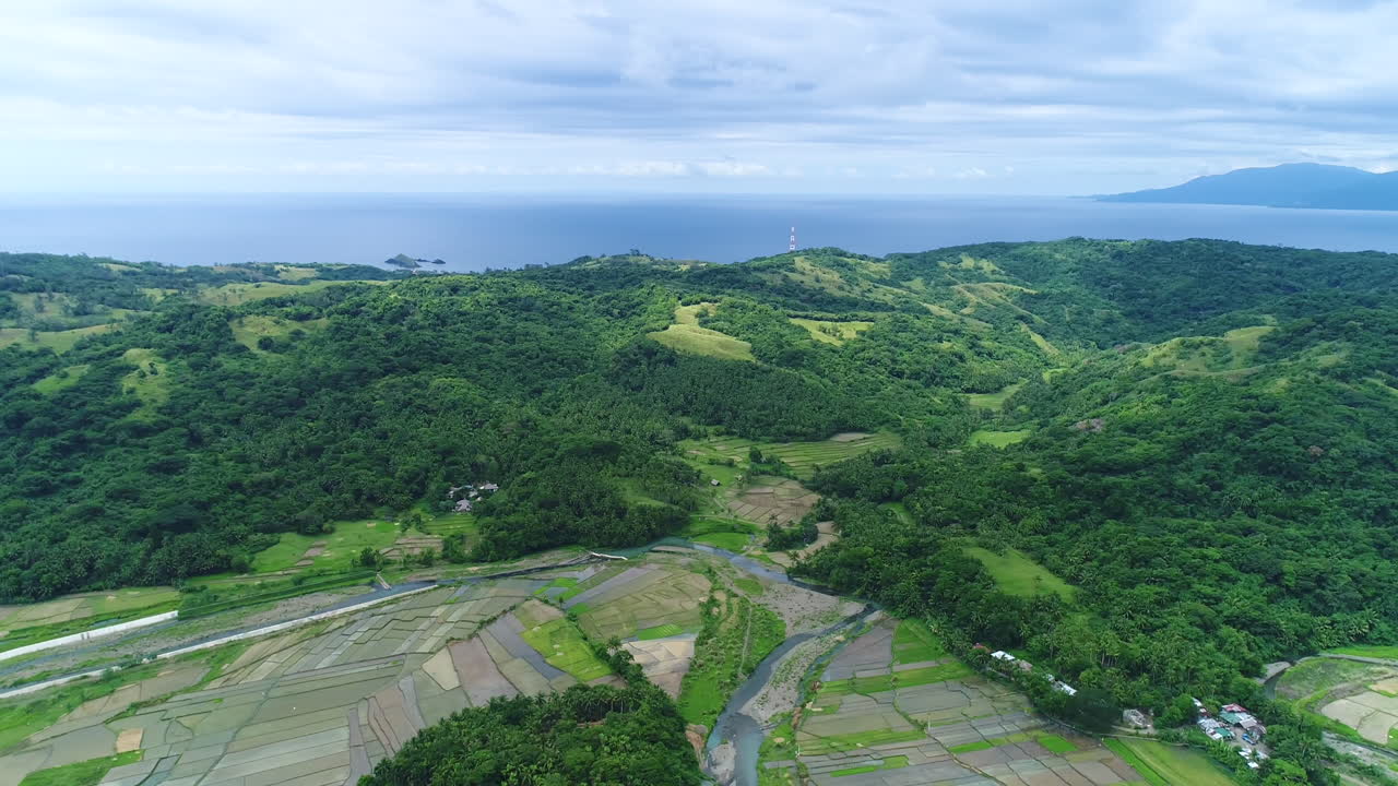 바다 근처 산 옆에 있는 농장의 넓은 패닝 공중 샷