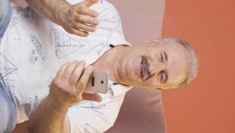 Vertical-video-of-Old-man-making-a-video-call-on-the-phone.