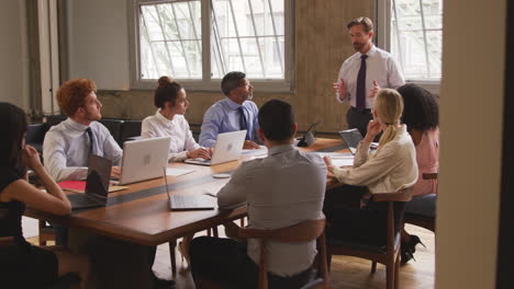 middle aged businessman leading a meeting, seen from doorway