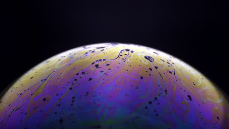 multicolored soap bubble planet in motion over black background