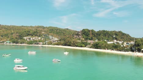 paradisiac ko phi phi don island bay with boats moored over warm turquoise waters, thailand - aerial fly-over showcase shot