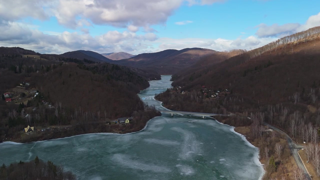 Ružínissa Itä-Slovakiassa jäätynyt tekojärvi sijaitsee kukkuloiden ja metsän ympäröimässä laaksossa lähellä Malý Folkmaria, kuvattuna lintuperspektiivistä pilvisen talvitaivaan alla