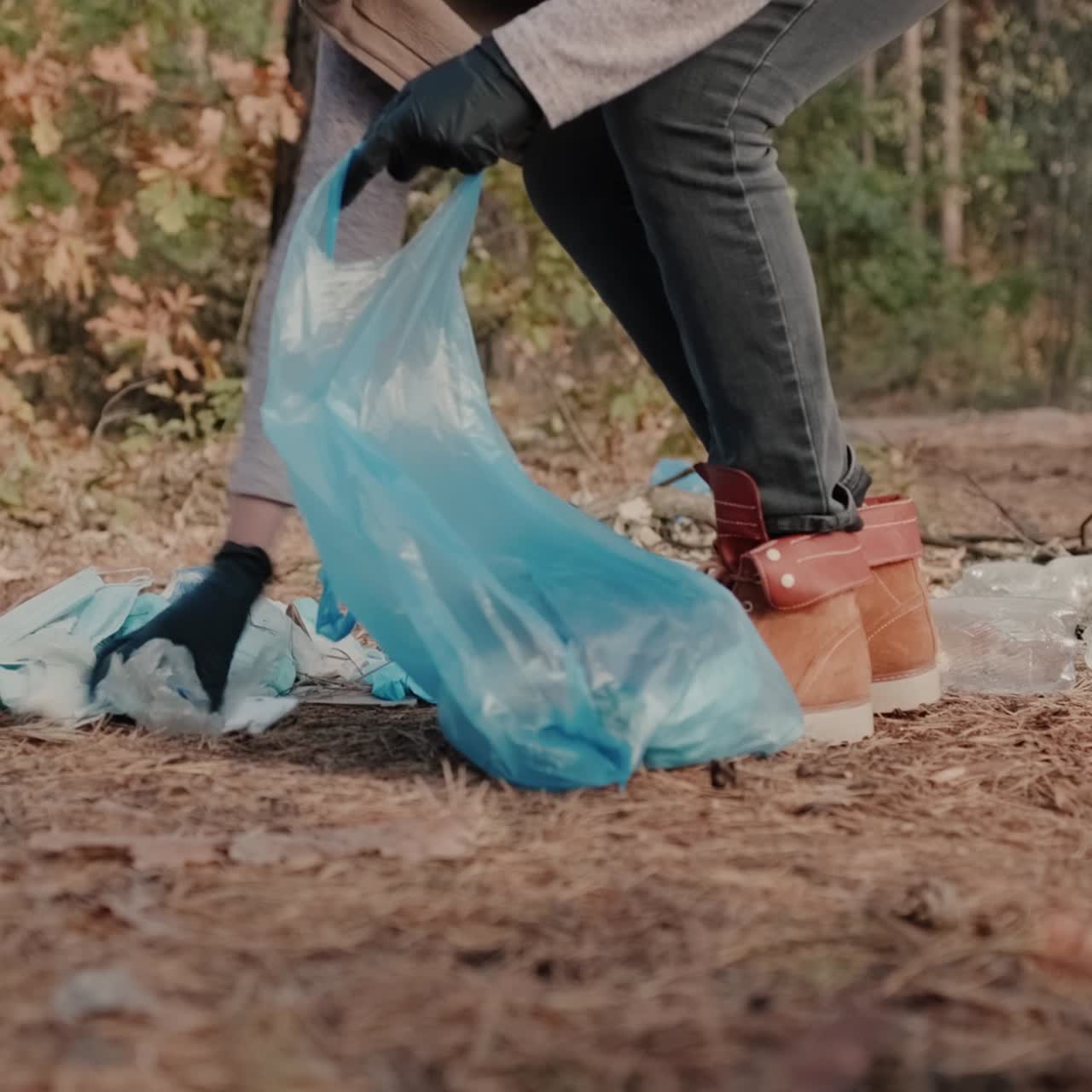 Una donna raccoglie mascherine mediche e rifiuti di plastica in una foresta