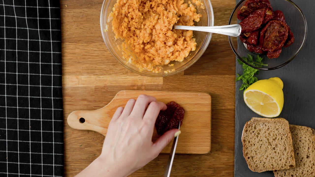 rebanar dos tomates secos para untar un sándwich vegetariano con pan de centeno