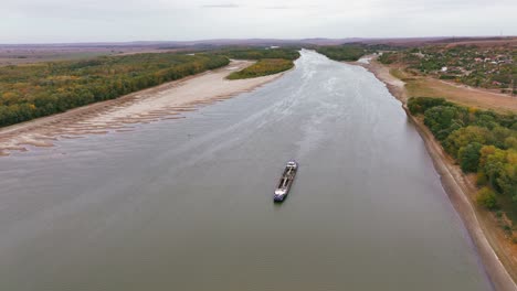 Toma-Aérea-De-Una-Draga-Que-Se-Desliza-A-Través-De-Un-Gran-Río,-Remodelando-El-Paisaje