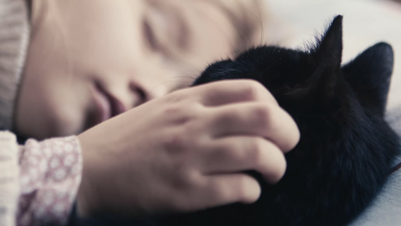 A girl falling asleep cuddling a black cat