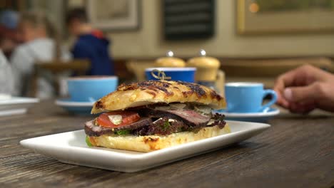 sándwich de ternera para el desayuno y cafés de fondo en un elegante café