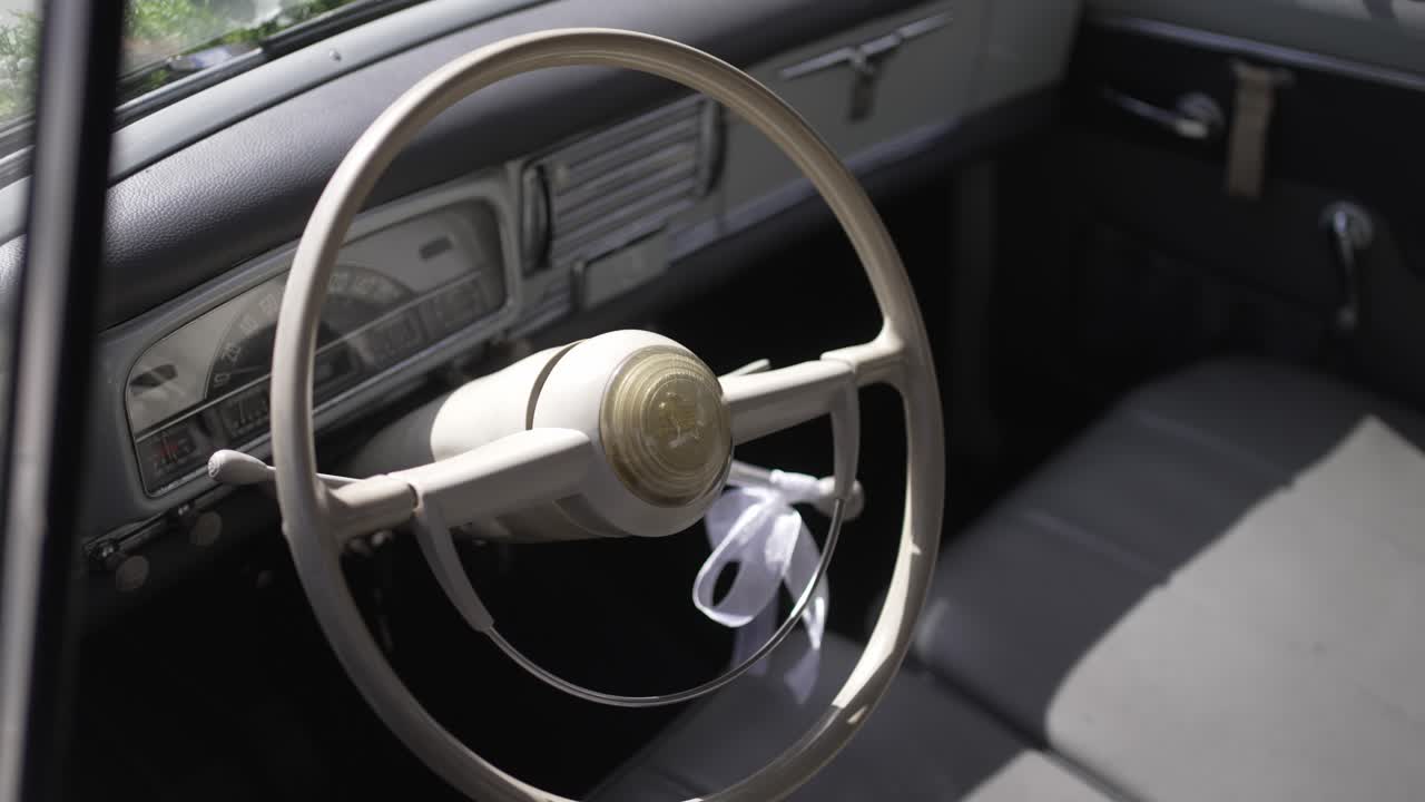 Close up of vintage car interior with old white steering wheel and ribbon detail
