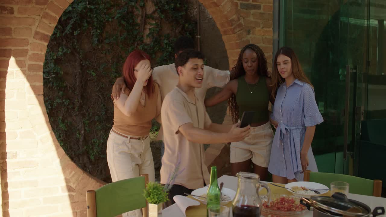 Diverse group of friends taking selfies and socializing at an outdoor gathering