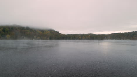 a drone flies over a quiet misty river in the fall season