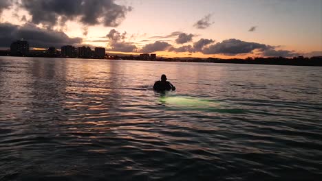 a scuba diver enters the water at sunset