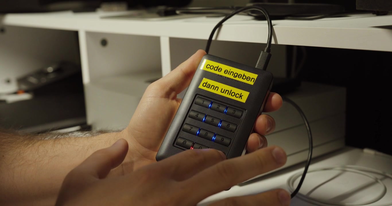 Close-up of a person entering a code on a keypad external hard drive to unlock secure data storage.