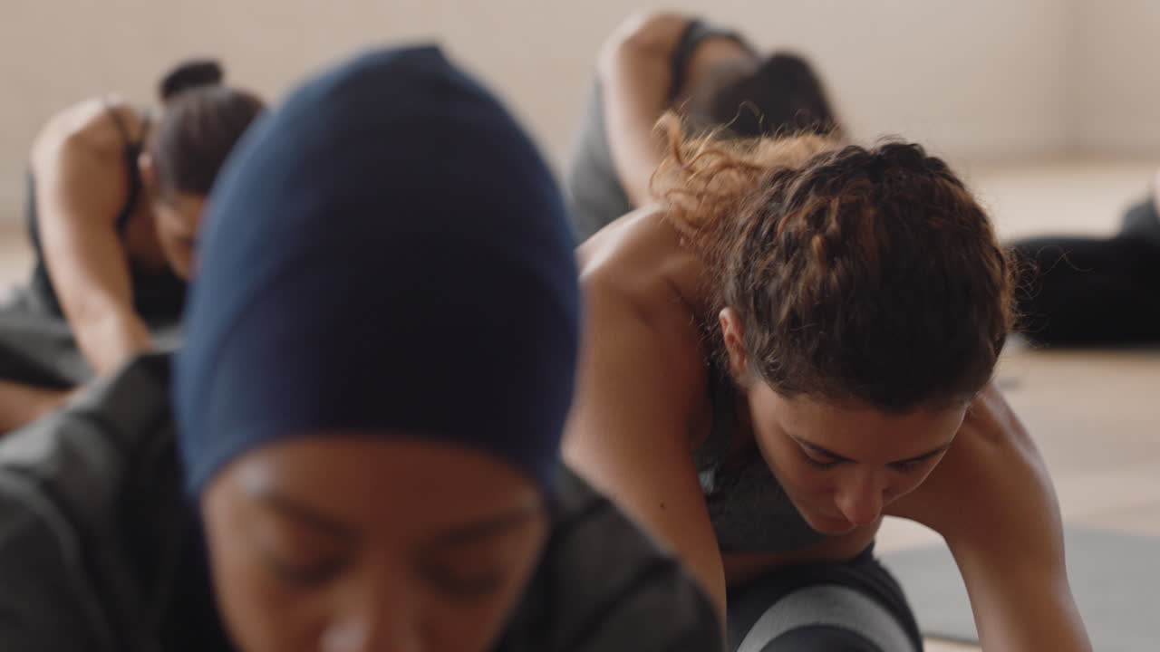 mujer de yoga saludable practicando de cabeza a rodilla pose de curvatura hacia adelante joven mujer caucásica disfrutando de un estilo de vida físico haciendo ejercicio en estudio con un grupo de mujeres multirraciales
