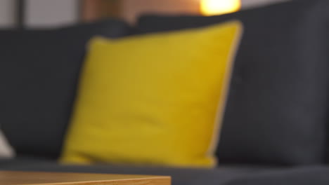 close up of man putting down gift wrapped present from table in lounge at home