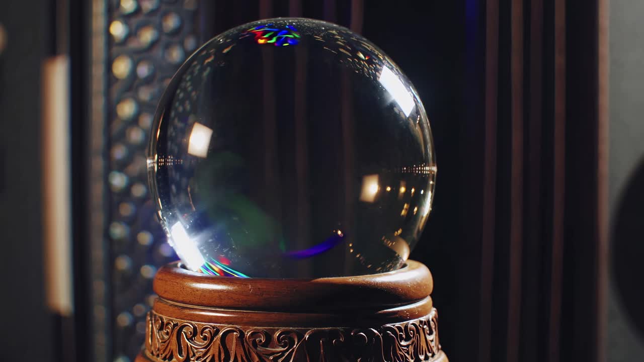 Close-up video of a crystal ball on an ornate wooden stand, capturing reflections and light