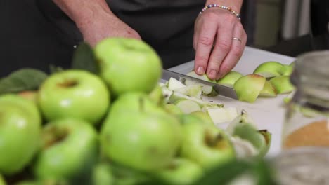 manos cortando manzanas verdes en porciones más pequeñas con un cuchillo afilado - primer plano, cámara lenta