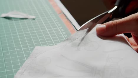 cutting fabric with scissors on a table and pushing away scraps