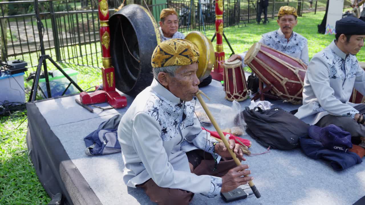 With weathered hands, flutes they bring, from the seruling, soft notes sing