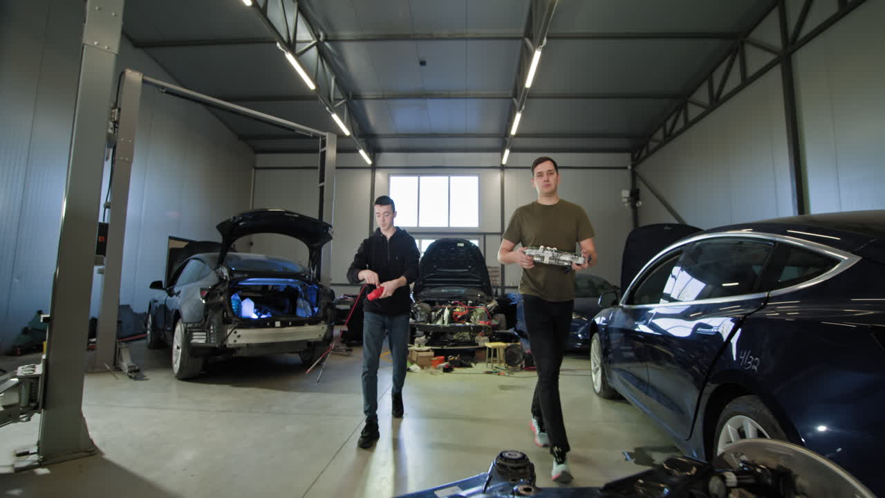 dos técnicos trabajando en una transmisión de vehículo eléctrico en un garaje