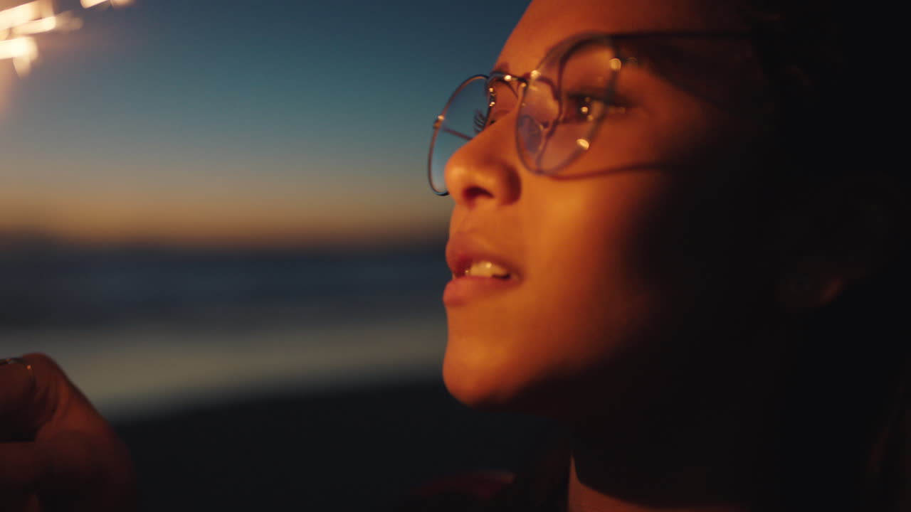 portrait mixed race girl holding sparkler on beach at sunset celebrating new years eve young woman enjoying  independence day celebration 4th of july