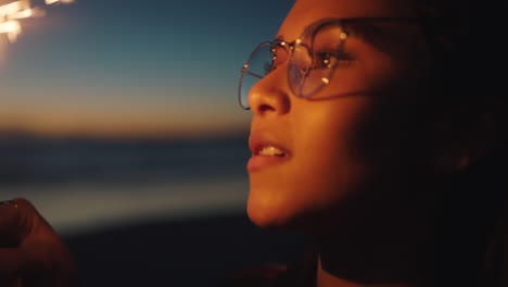retrato chica de raza mixta sosteniendo bengala en la playa al atardecer celebrando la víspera de año nuevo joven disfrutando de la celebración del día de la independencia el 4 de julio